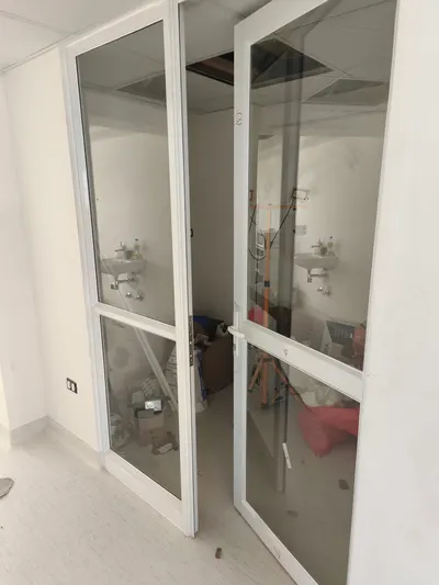 Puertas de aluminio blanco con cristal transparente que dan a un baño en obra