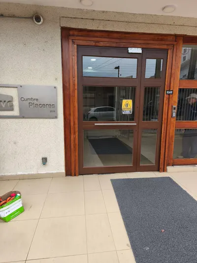 Puerta doble de aluminio imitación madera con montante vidriado en el acceso de un edificio