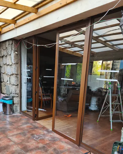 Puertas plegables y correderas de aluminio imitación madera que cierran una terraza techada